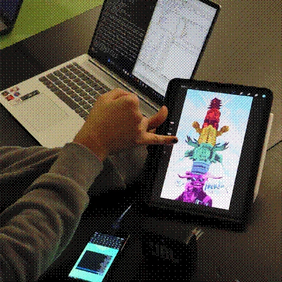 A student showcasing his work on an iPad, next to it his Laptop and the server phone.