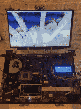 A modified laptop with a transparent front cover displaying the inside of the laptop. Attached a character display. The main screen is displaying web cam footage that is being converted live to ASCII characters.